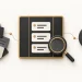 An ordered task board beside a scattered card stack, magnifying glass and target.