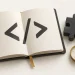 An open code notebook beside learning blocks and a gold compass.